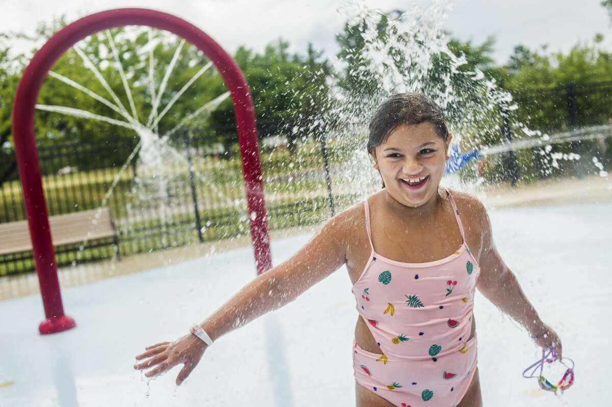 Yashi Weiler, 9, stands underneath a fountain during a day camp Wednesday, July 22, 2020 at Greater Midland Community Center. (Katy Kildee/kkildee@mdn.net)