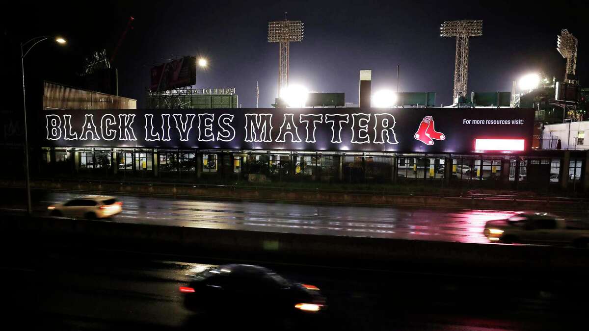 Cars along the Massachusetts Turnpike drive past a giant "Black Lives Matter" mural, Wednesday evening, July 22, 2020, outside Fenway Park, at the rear, in Boston. (AP Photo/Charles Krupa)