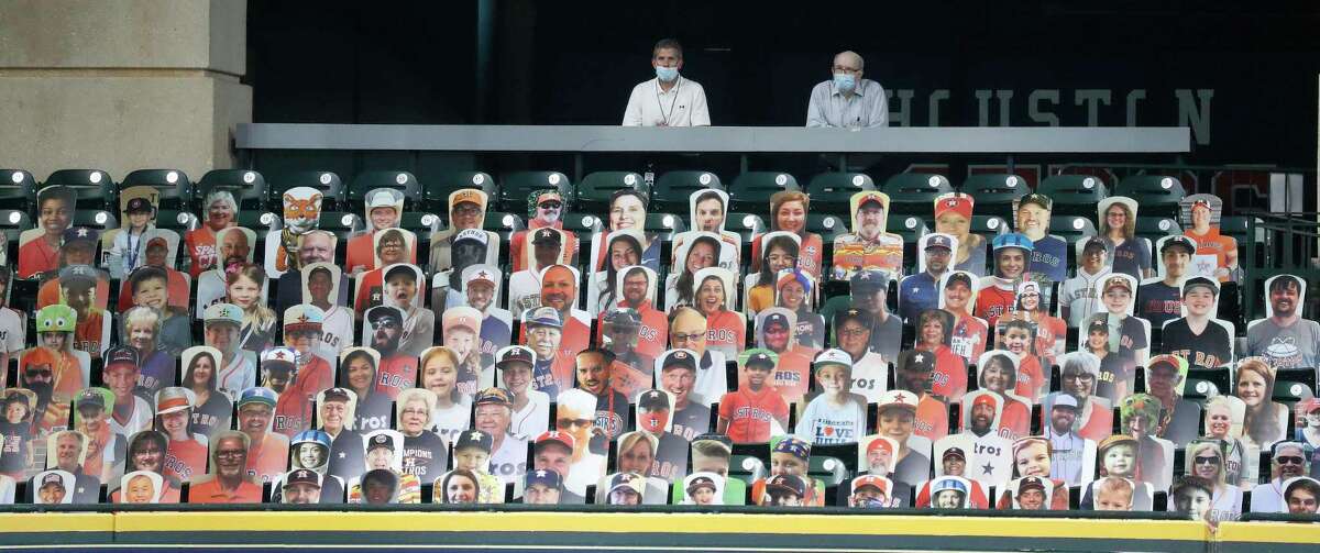 Two live men stand behind a section of cardboard cutouts of Astros fans in the Crawford Boxes during an intrasquad game during the Astros summer camp at Minute Maid Park, Wednesday, July 22, 2020, in Houston.