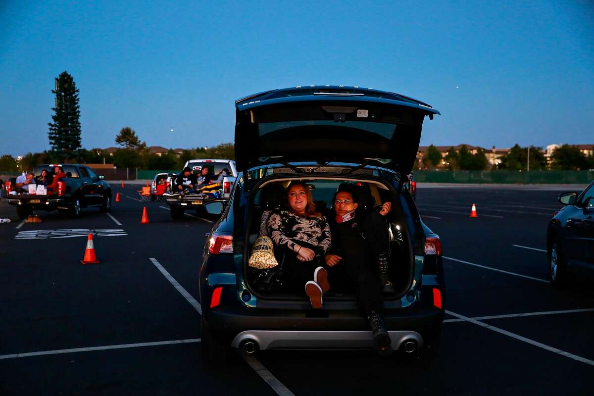 Nina L and Jon R (right) prepare to watch The Shining from the back of their car at the Drive In theater at the San Mateo County Event Center on Saturday, July 18, 2020 in San Mateo, California. We know know that certain behaviors are safe like going to a drive in movie.