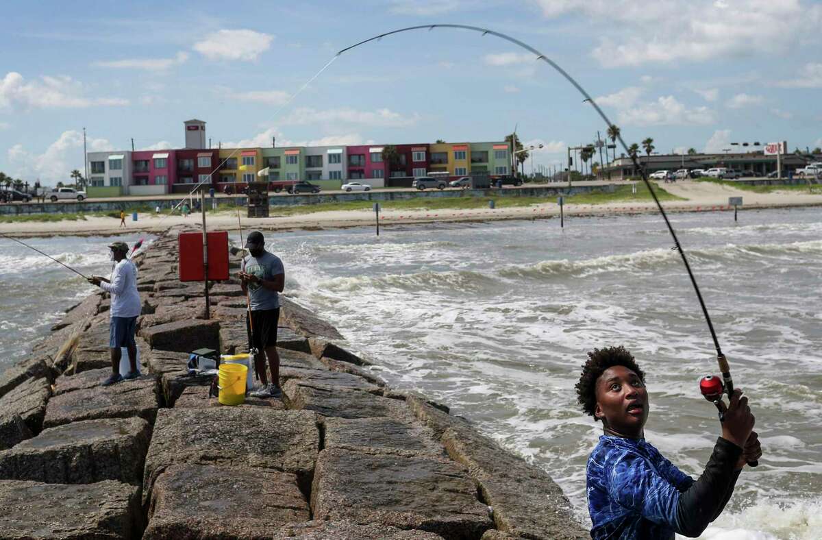 Jaden Simmons, right, 14, casts his line into the sea as he fishes with his father, Riley Simmons, center, and his great-uncle Orthell Rivers, left, on Thursday, July 23, 2020, at the beach in Galveston.