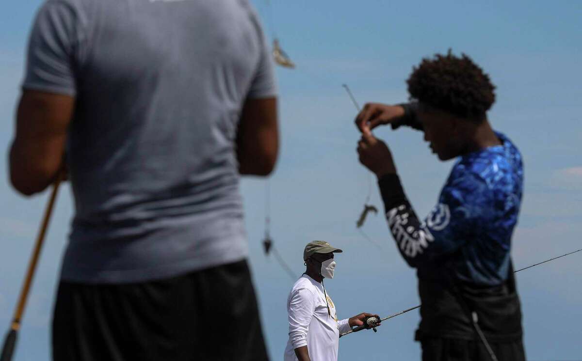 Orthell Rivers, center, fishes with his nephew Riley Simmons, left, and Simmons' son Jaden Simmons, 14, on a jetty Thursday, July 23, 2020, at the beach in Galveston.