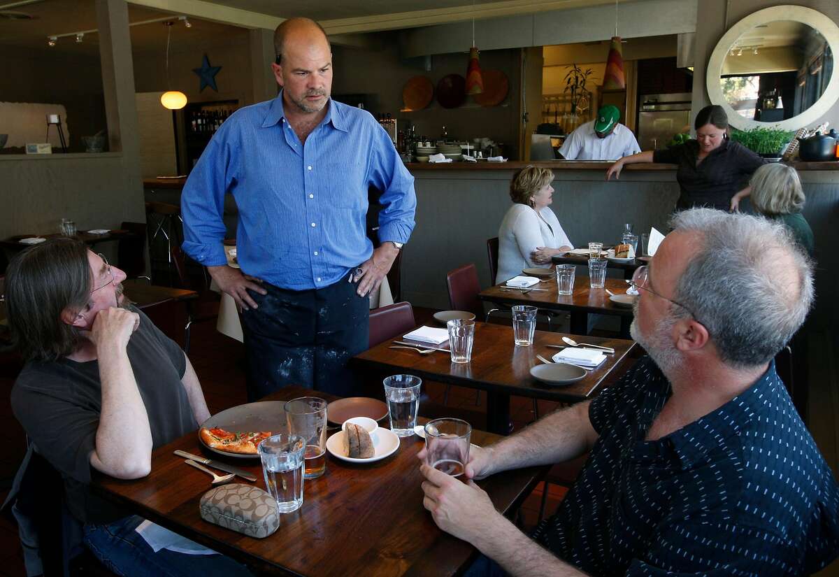 2010年6月11日星期五，Osteria Stellina餐厅的主厨兼老板Christian Caiazzo在他位于加州雷耶斯角站的餐厅里与顾客Keith Ggor(左)和Tony Magee(右)聊天。Caiazzo还拥有并经营着街对面Toby's Feed Barn的咖啡馆。