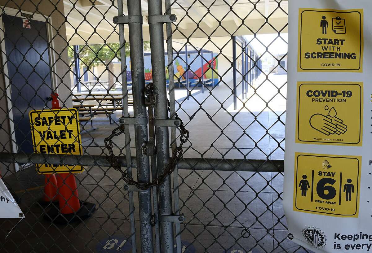 A chain link fence lock is see on a gate at a closed Ranchito Elementary School in the San Franando Valley section of Los Angeles on Monday, July 13, 2020. Amid spiking coronavirus cases, Los Angeles Unified School District campuses will remain closed when classes resume this August, Superintendent Austin Beutner said Monday.(AP Photo/Richard Vogel)