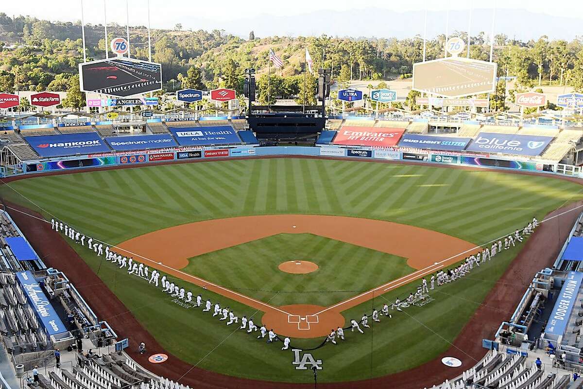 LOS ANGELES, CALIFORNIA - JULY 23: Members of the Los Angeles Dodgers and the San Francisco Giants kneel prior to the national anthem before their game at Dodger Stadium on July 23, 2020 in Los Angeles, California. (Photo by Harry How/Getty Images)