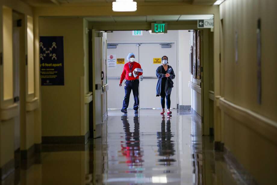 Rodney Garrick (left) and Jennifer Carton-Wade walk down the hallway at Laguna Honda hospital in June. Photo: Gabrielle Lurie / The Chronicle