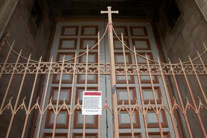 A sign states that all weekday and weekend masses are canceled hangs on the front gates of SS Peter and Paul’s Church in San Francisco. City officials had complained of the church’s practice of holding Mass in defiance of health orders.