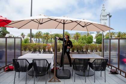 Jiang Rong, a busser at Harborview Restaurant and Bar, cleans and disinfects partitions between tables on Friday. A restaurant spokeswoman said it had not been told of guests who became infected days after a wedding whose rehearsal dinner was held there.