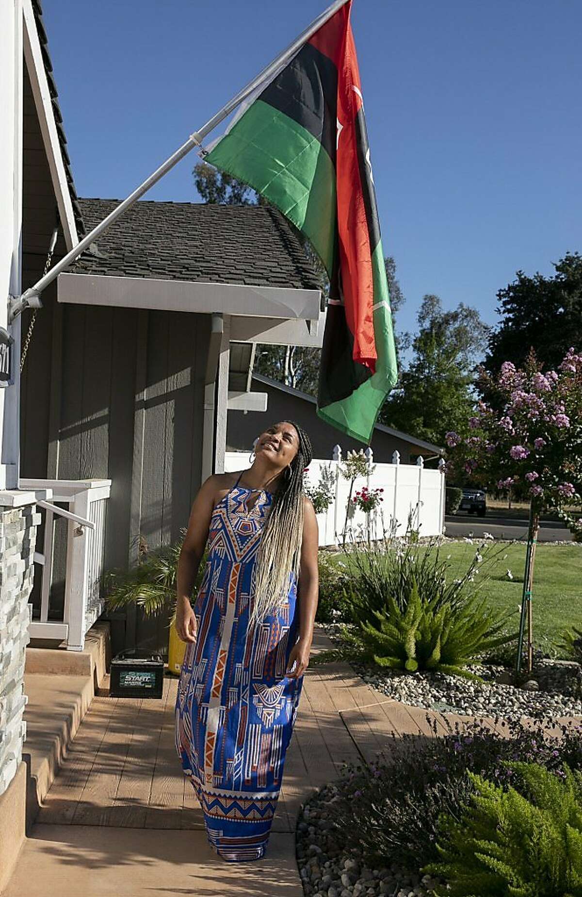 Sharie Wilson stands below the Pan African flag outside of her Elk Grove home on June 22, 2020. Wilson says that she raised the flag to celebrate Juneteenth as a way to help educate her neighbors about the holiday.