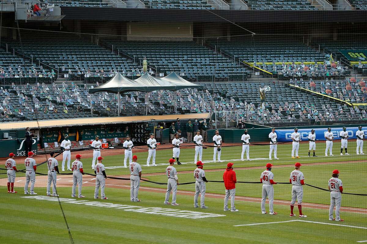 Oakland Athletics and Los Angeles Angels members hold a black rope during Black Lives Matter moment before season opener at Oakland Coliseum in Oakland, Calif., on Thursday, July 24, 2020.