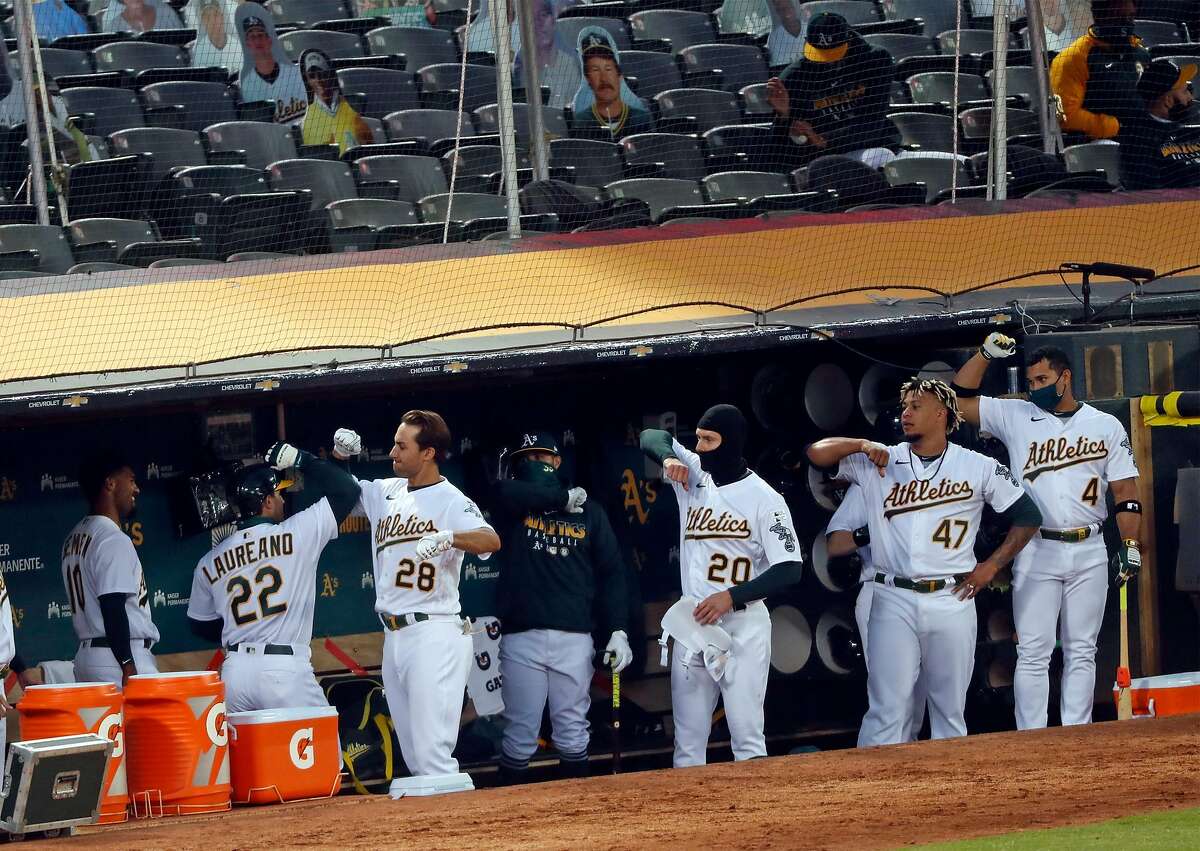 Oakland Athletics' Ramon Laureano is greeted by Matt Olson and teammates in dugout after Laureano's 4th inning home run against Los Angeles Angels during MLB game at Oakland Coliseum in Oakland, Calif., on Friday, July 24, 2020.
