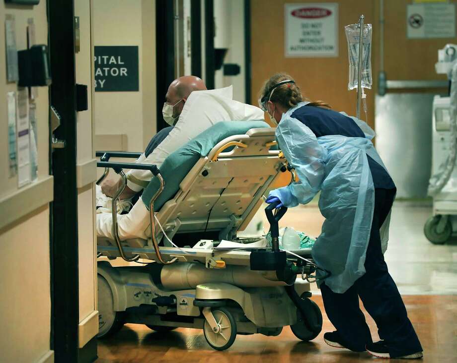 Trish Trevino, a nurse in the emergency room at Christus Santa Rosa, wheels a COVID-19 patient to a hospital room on July 14, 2020. A surge in coronavirus patients in June and July has brought hospitals in San Antonio close to full capacity. / ©2020 San Antonio Express-News