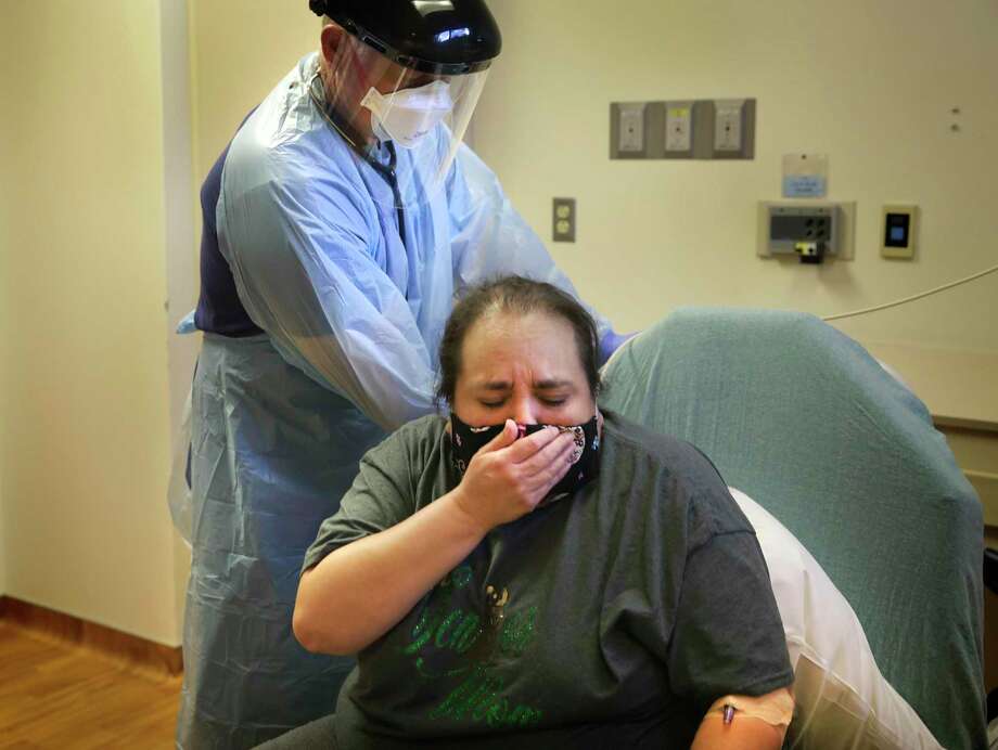 Melissa Paez-Villarreal, who has COVID-19, covers a cough as Dr. Corey Harrison, medical director of the emergency department at Christus Santa Rosa Hospital-Medical Center, checks her vital signs in the emergency room on July 20, 2020. He has to decide which patients need to be hospitalized or sent home to recover. Photo: Bob Owen /San Antonio Express-News / ©2020 San Antonio Express-News