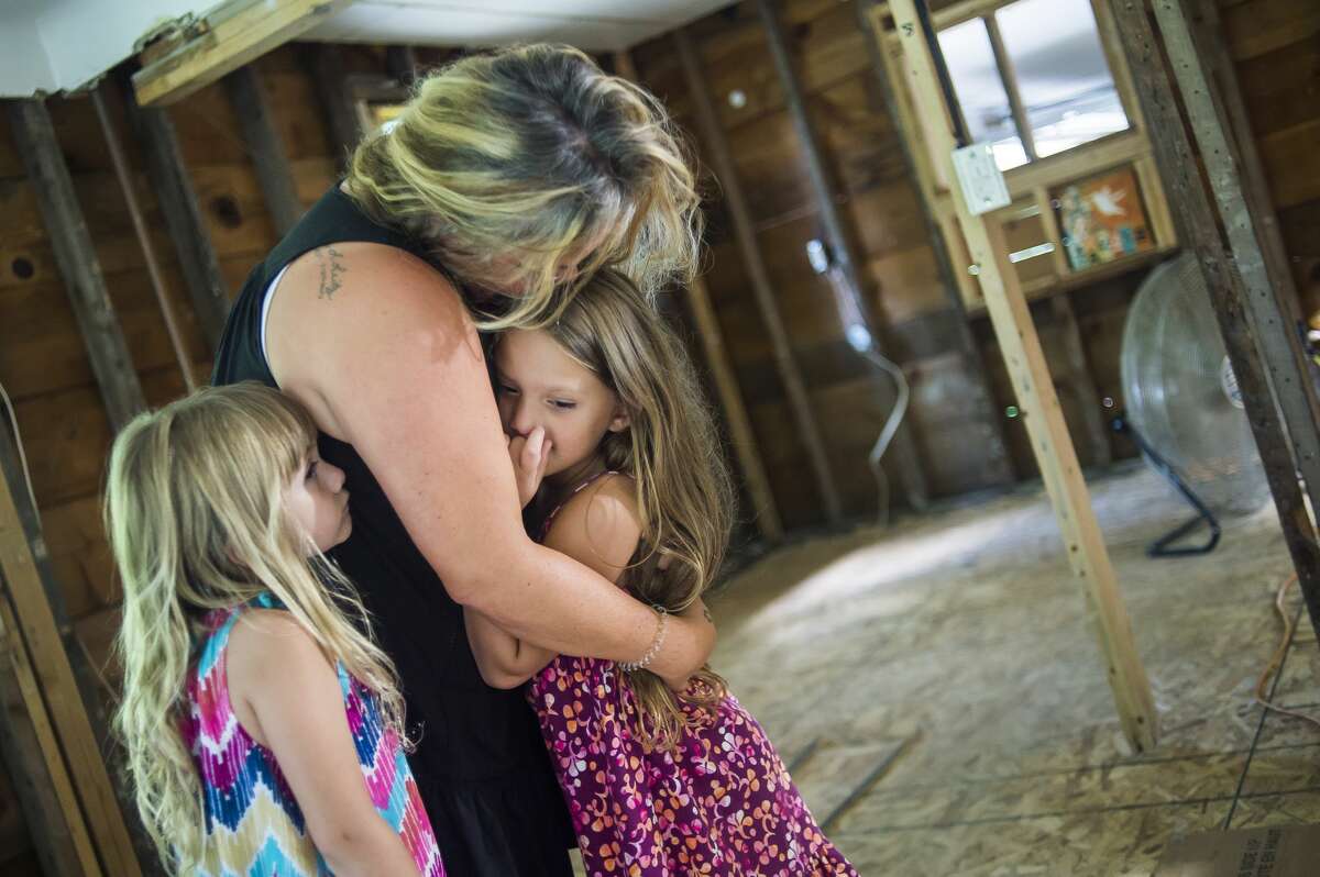 Amy Thomas cradles her daughters, Naomie, 5, left, and Nadeah, 6, right, Friday, July 24, 2020 on the first floor of their home, which is still being renovated after it was devastated by the flooding in May. (Katy Kildee/kkildee@mdn.net)