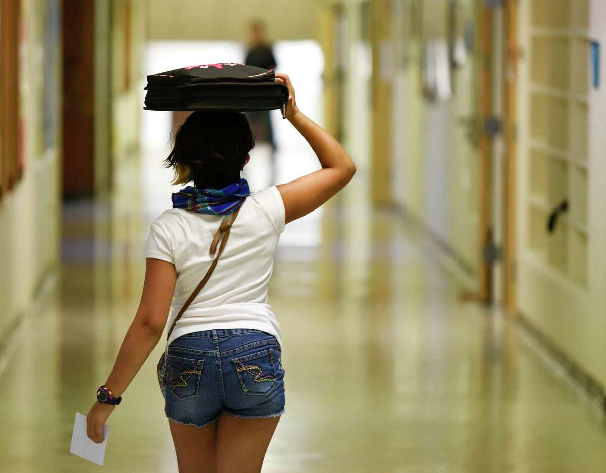 A student balances a binder on her head while walking through the halls on the first day of school at Eastern Middle School in Greenwich, Conn. Wednesday, Sept. 2, 2015.