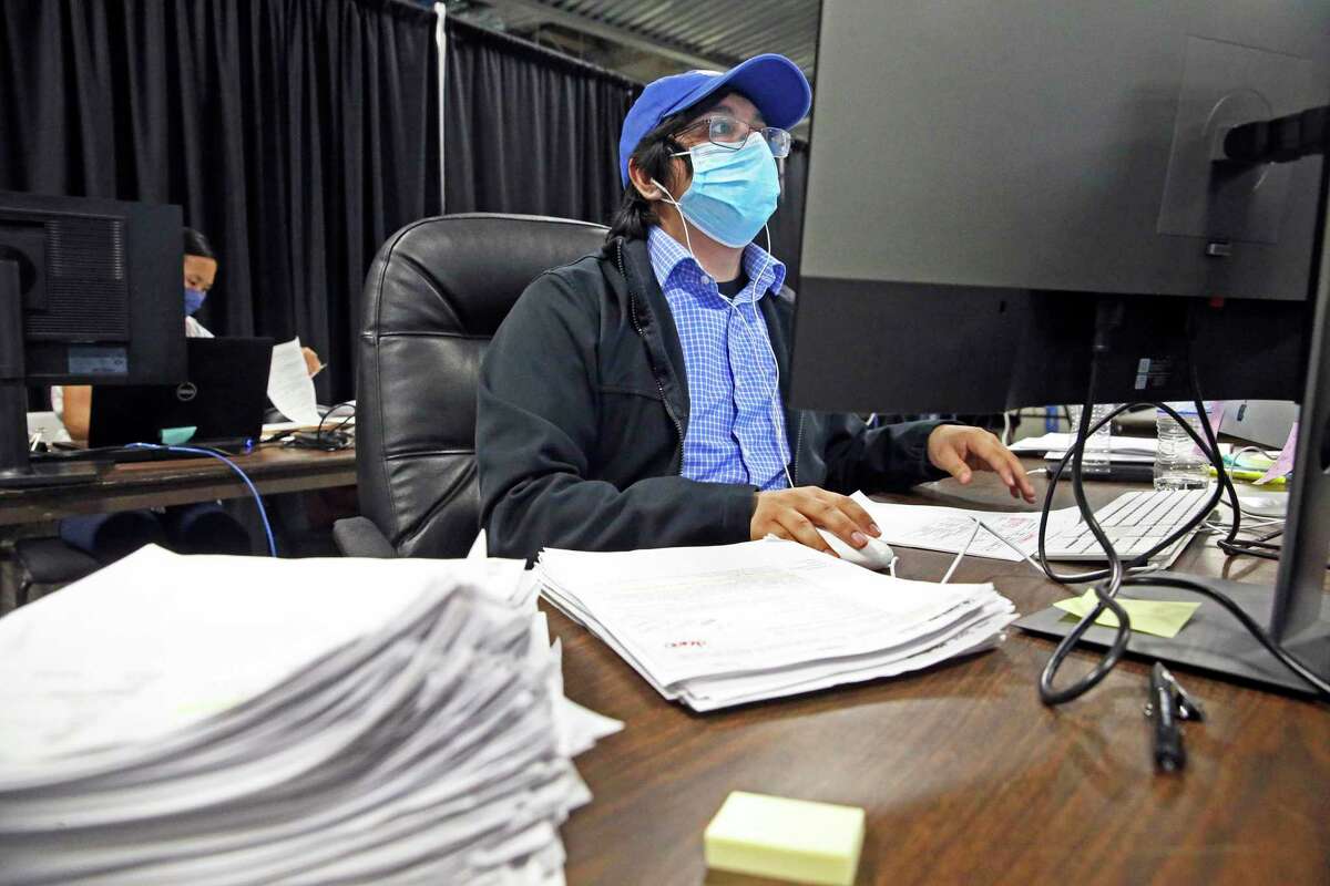 An investigator works through stacks of new records as Metro Health ramps up its contact tracing effort with a large work space in the Alamodome.