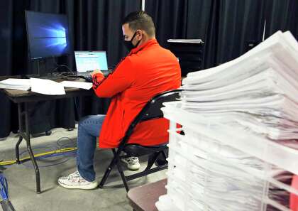 Program specialist Chris Dillon works behind a stack of cases managing data entry and analytics for contact tracing.