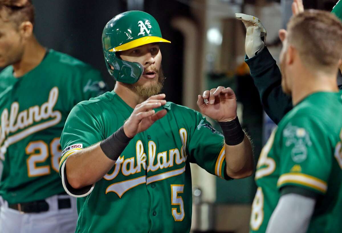 Oakland Athletics' Chris Herrmann returns to dugout after scoring on Jurickson Profar's double in 7th inning against Milwaukee Brewers during MLB game at Oakland Coliseum in Oakland, Calif., on Wednesday, July 31, 2019.