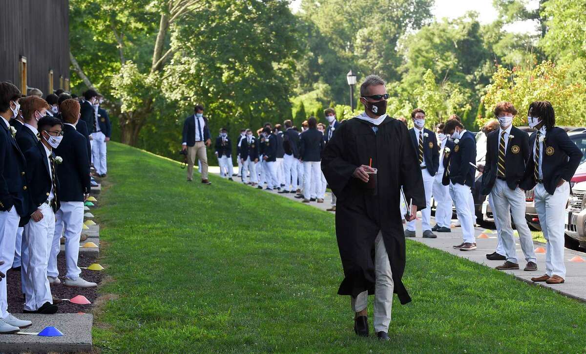 Brunswick School Head of School Thomas Philip chats with students as he makes his way to start the One hundred and Eighteenth Commencement ceremony on Cosby Field July 25, 2020 at the school in Greenwich, Connecticut. The faculty also missed seeing the memorable Class of 2020 after the students moved to remote learning in mid-March. “As I think about you, it’s not only you that were cheated this spring,” Philip said. “We were all cheated with close to two months of not seeing the young men of our school. Days we will never get back, days that we will sorely miss. Senior spring is a special phenomenon in a school like Brunswick. It passes swiftly, but it is filled with special moments that make lasting memories.”