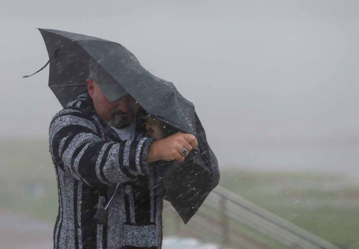 A man holds the front on his umbrella as he fights heavy rain and wind on Seawall Boulevard on Saturday, July 25, 2020, in Galveston, Texas. Outer bands of Hurricane Hanna are affecting the Houston and Galveston areas.
