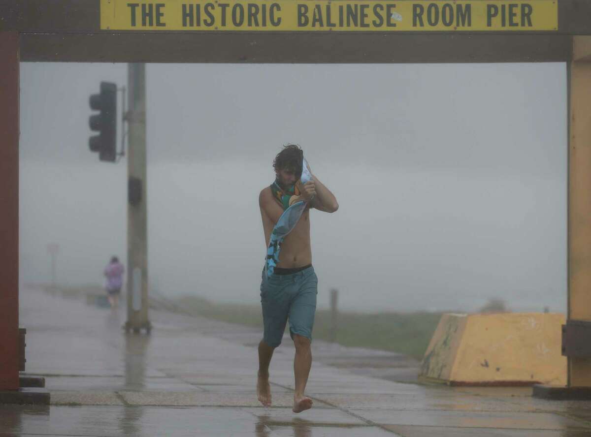 Devin Brown uses a towel to cover his face from heavy rain and wind on Seawall Boulevard on Saturday, July 25, 2020, in Galveston, Texas. Outer bands of Hurricane Hanna are affecting the Houston and Galveston areas.