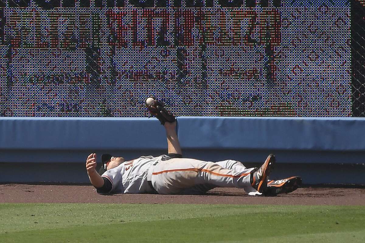 San Francisco Giants left fielder Austin Slater lays on the ground after making a catch on a ball hit by Los Angeles Dodgers' Corey Seager during the sixth inning of a baseball game Saturday, July 25, 2020, in Los Angeles. (AP Photo/Mark J. Terrill)