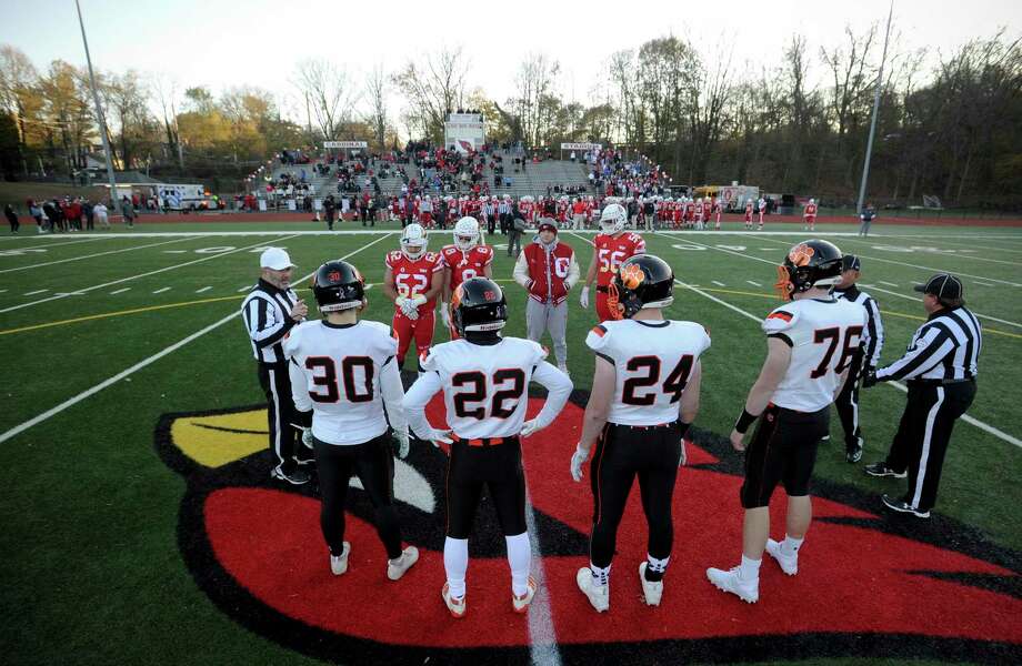 Team captains from both Ridgefield and Greenwich participate in the coin toss with head referee Terry Newall at midfield prior to the start of a high school football game in November. Photo: Matthew Brown / Hearst Connecticut Media / Stamford Advocate