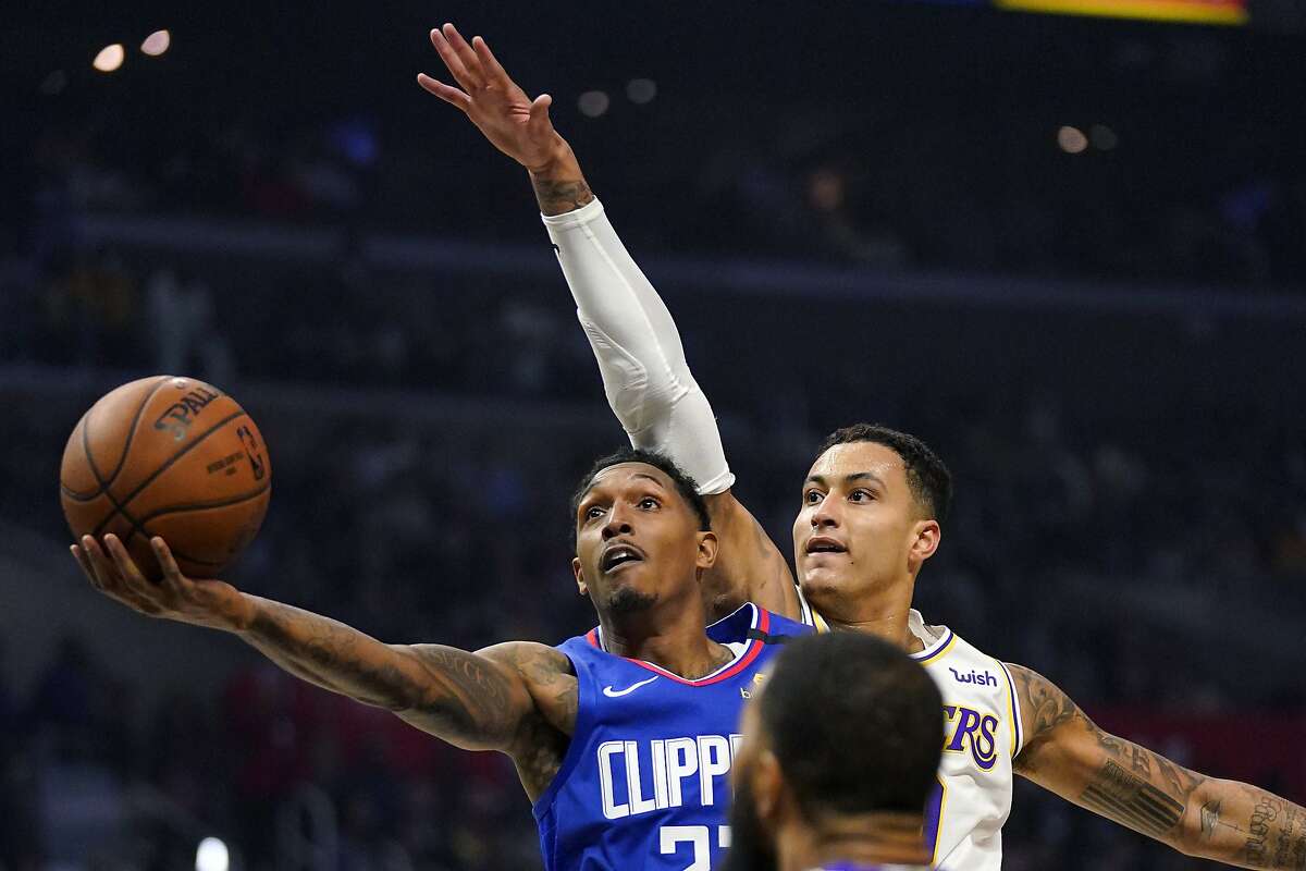 FILE - In this March 8, 2020, file photo, Los Angeles Clippers guard Lou Williams, left, shoots as Los Angeles Lakers forward Kyle Kuzma defends during the first half of an NBA basketball game in Los Angeles. (AP Photo/Mark J. Terrill, File)