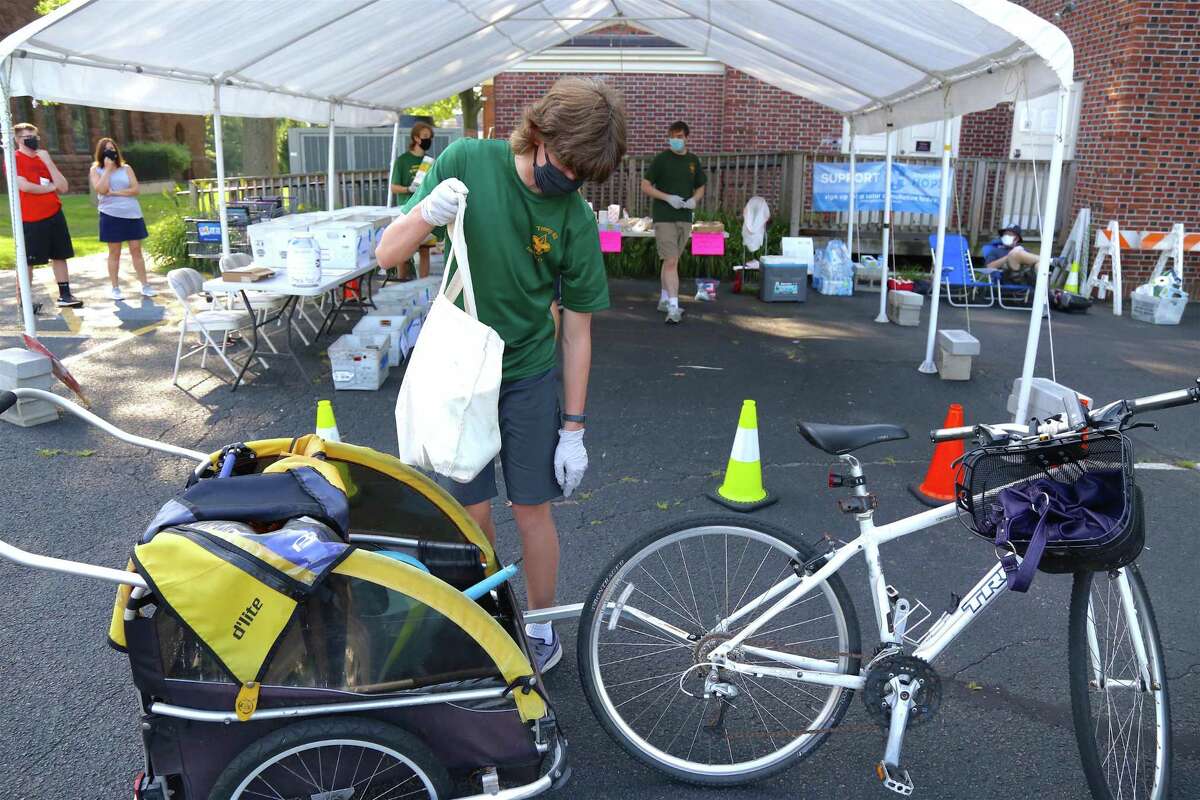 Simon Weber, 15, of Fairfield gets stuff being dropped off by bicycle at the Boy Scouts' food drive for Operation Hope at its food pantry on Saturday, July 26, 2020, in Fairfield, Conn.
