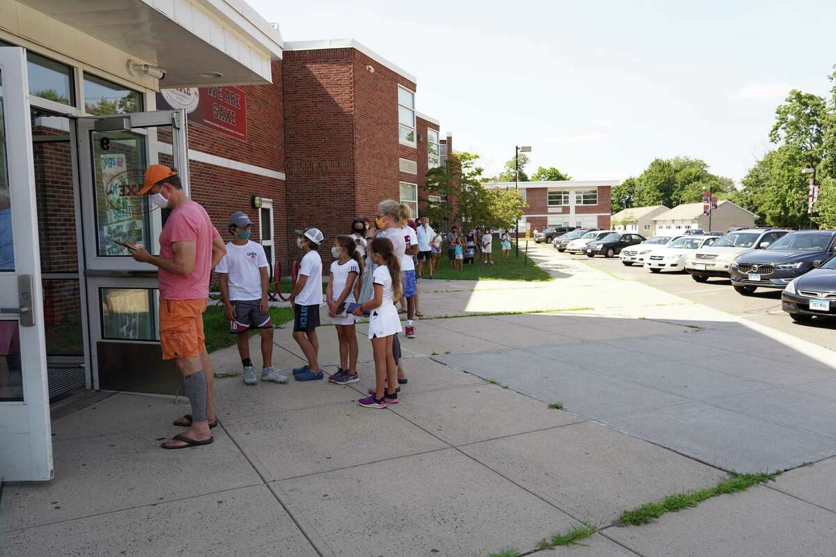 The line of people waiting to be tested for the coronavirus stretches to the far end of Saxe Middle School in New Canaan, and is beginning to wrap around the west end of the building on Monday, July 27, during the town’s latest drive-thru testing for the virus. The next opportunity for town residents to be tested is Aug. 3.