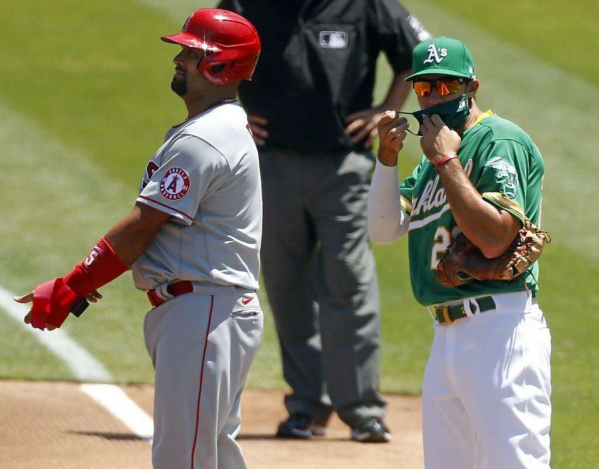 Oakland Athletics' Matt Olson puts on a mask after Los Angeles Angels' Albert Pujols singled in 2nd inning in MLB game at Oakland Coliseum in Oakland, Calif., on Monday, July 27, 2020.