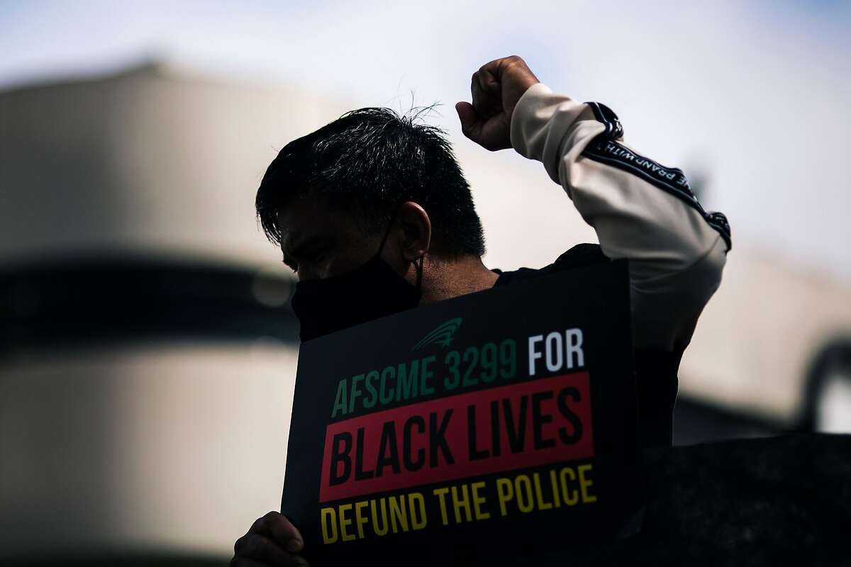 A protester raises his fist during a demonstration outside the San Francisco Police Officers Association against the POA's role in support of systematic racism and calling for the defunding of the police on Monday, July 27, 2020 in San Francisco, California.