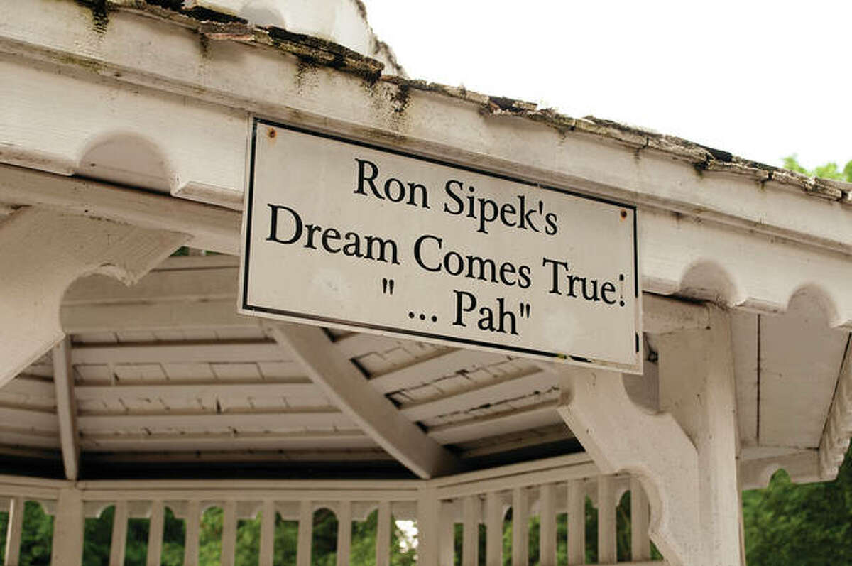 A sign on the gazebo reads, “Ron Sipek’s Dream Comes True: ‘… Pah’.” “Pah” is an American Sign Language idiom that means “finally” or “success at last.”