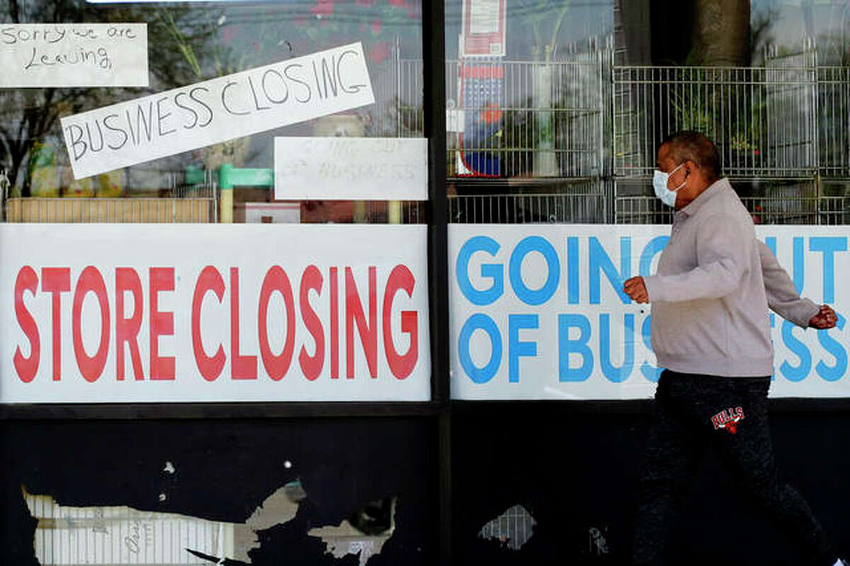A man looks at signs of a closed store due to COVID-19 in Niles. A new report indicates more businesses in Illinois are choosing to close permanently rather than temporarily.