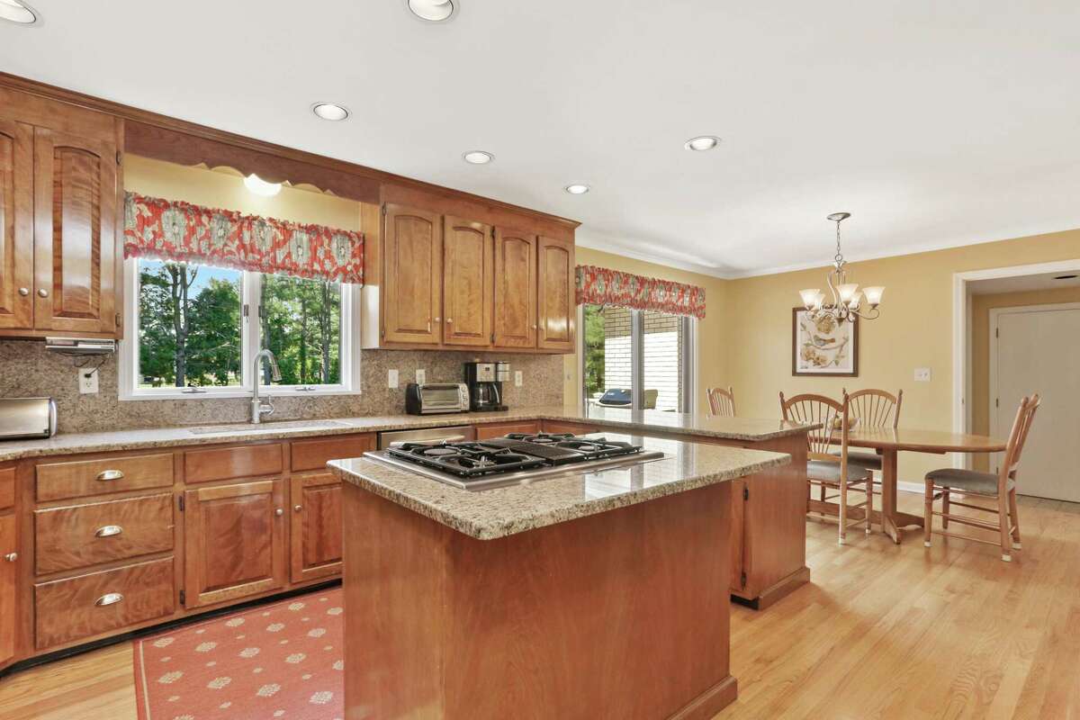 In the kitchen there is a small center island, granite counters, quite a few cabinets, and stainless steel appliances. The formal dining room has a wall of built-ins for storage and display of china. It also has French doors into a large sun room. The kitchen is sandwiched between the dining room and the casual breakfast area, the latter of which has sliding doors to the large raised deck and backyard. The sun room has sliding doors to the same deck as well as a ceiling fan and two walls of nearly floor-to-ceiling casement windows. In the kitchen there is a small center island, granite counters, quite a few cabinets, and stainless steel appliances.