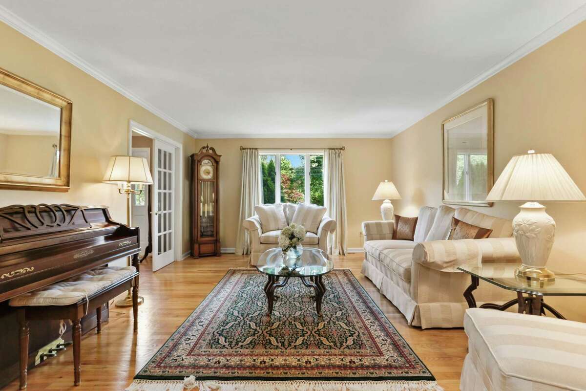 French doors separate the foyer from the formal living room. The 10-room house was built in 1984 on a corner lot of Ridgeway Road, an attractive tree-lined cul-de-sac, with one side of the property bordering Sport Hill Road (Route 59). Its location places this house only a few miles and minutes from the Merritt Parkway as well as shopping and dining in one direction, and the center of town in the other. Quarried stone pillars topped with lanterns mark the entrance to the paved driveway, which provides ample parking in addition to the attached two-car garage.