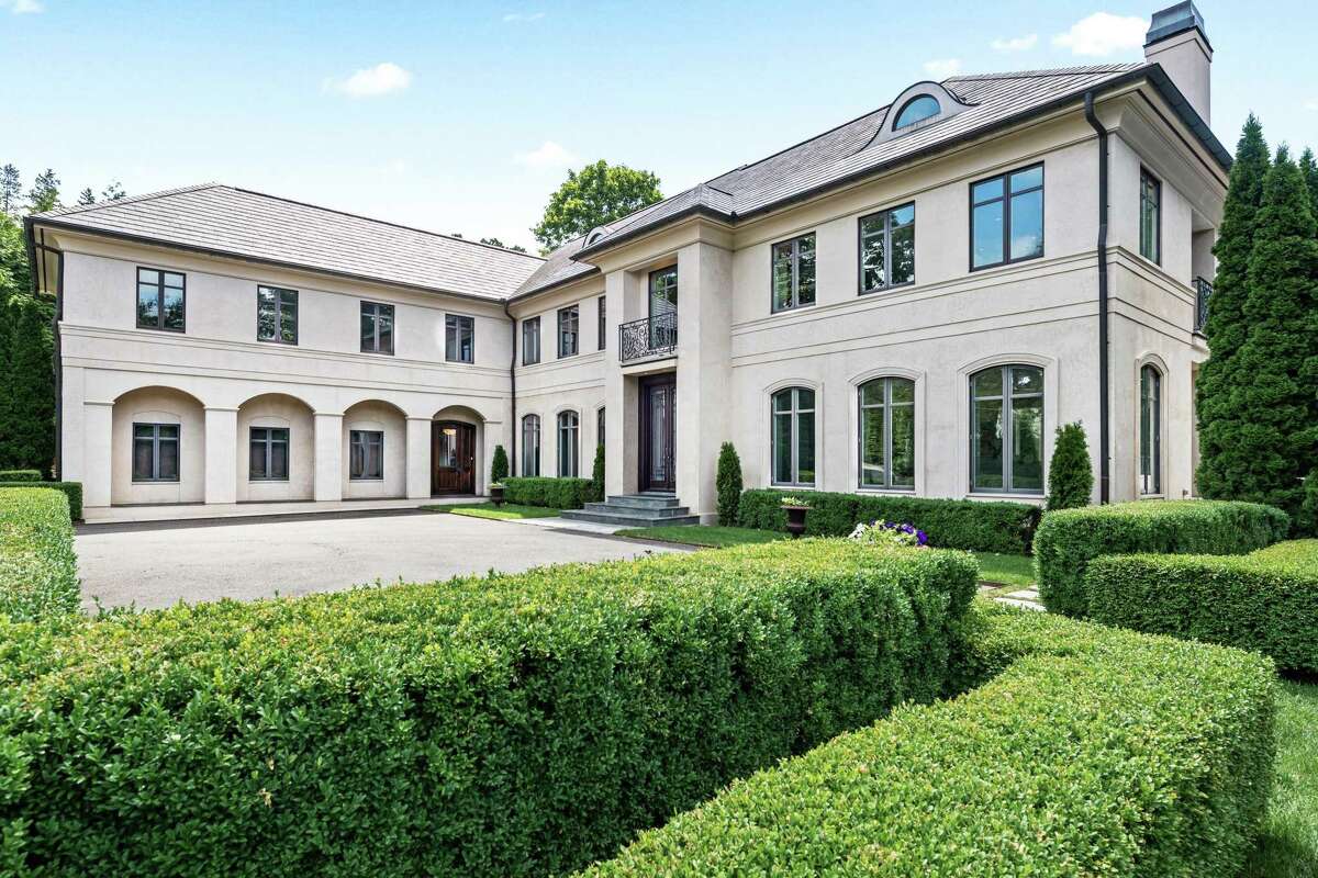 The tan-colored custom-built concrete, stucco and stone modern colonial house at 8 Brookside Drive features 14 rooms and 11,853 square feet of living space.