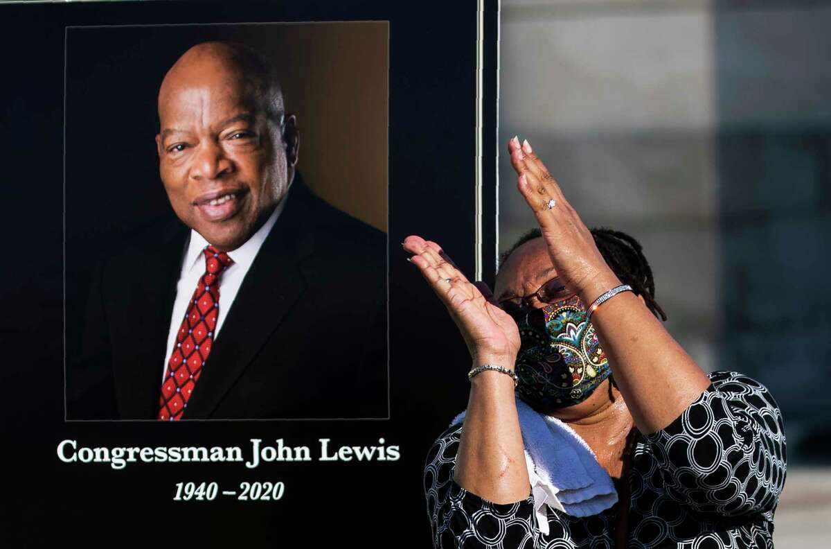 Jaquenette Ferguson from Oxon Hill, Md., gestures as she gets her picture taken beside a portrait of the late Rep. John Lewis, D-Ga., near the East Front Steps of the U.S. the Capitol, Tuesday, July 28, 2020, in Washington.