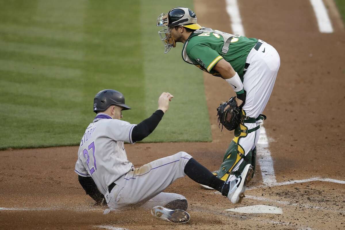 Colorado Rockies' Trevor Story, left, slides to score past Oakland Athletics catcher Austin Allen during the third inning of a baseball game Tuesday, July 28, 2020, in Oakland, Calif. (AP Photo/Ben Margot)