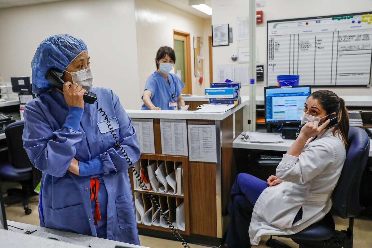 Nurses Regina Truong (left) and Liz Philips (right) talk on the phone as they work on the Covid-19 floor at Saint Francis Hospital in San Francisco on Monday, April 6, 2020.