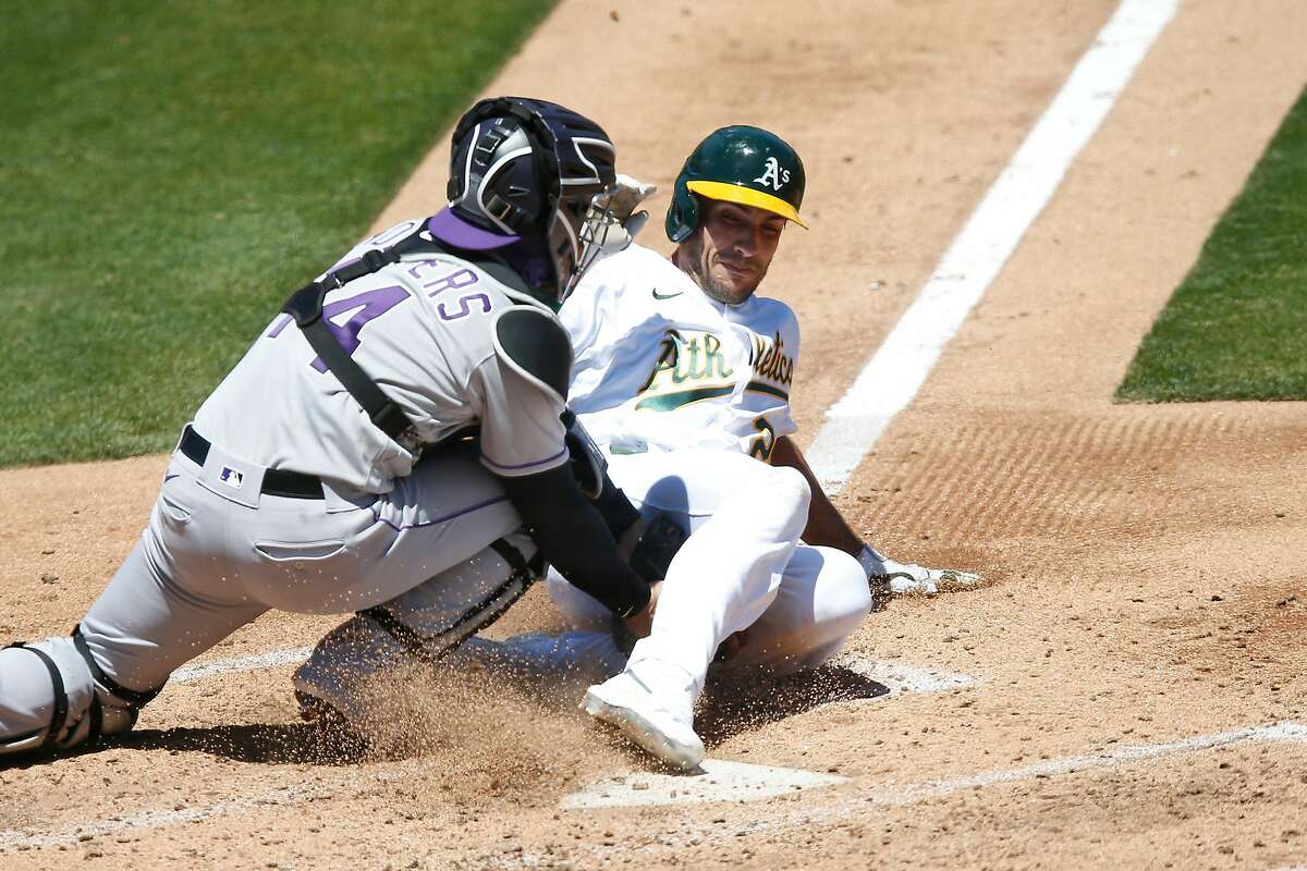 OAKLAND, CALIFORNIA - JULY 29: Matt Olson #28 of the Oakland Athletics is tagged out while running to home plate by catcher Tony Wolters #14 of the Colorado Rockies in the bottom of the fourth inning at Oakland-Alameda County Coliseum on July 29, 2020 in Oakland, California. (Photo by Lachlan Cunningham/Getty Images)