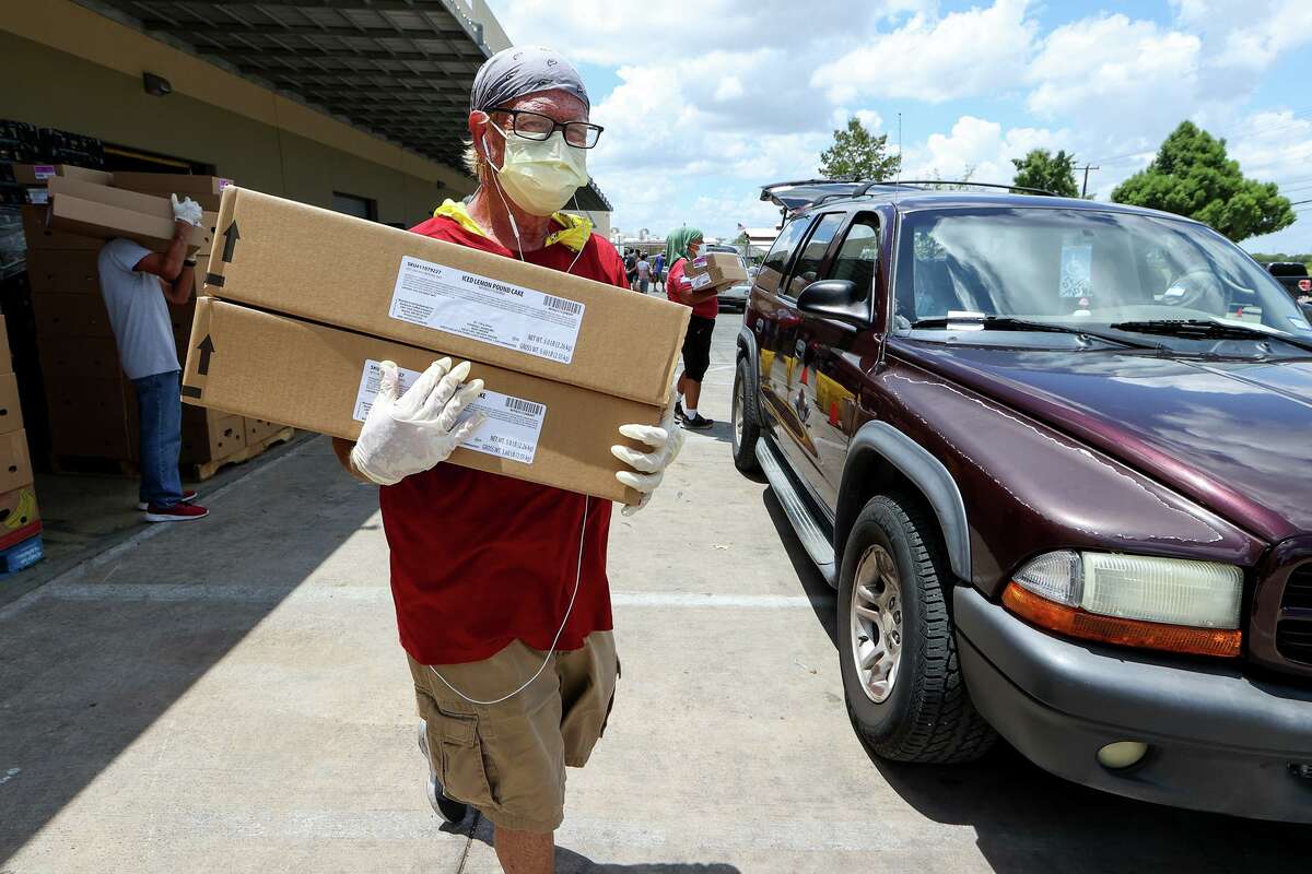 Wayne Poisson carries boxes of food items to a waiting family while volunteering at the San Antonio Food Bank in July.