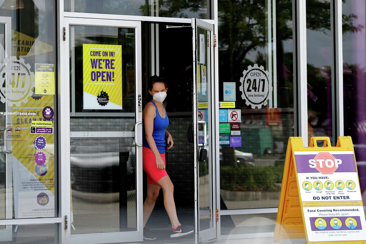 A person wears a mask while leaving a Planet Fitness gym location. Planet Fitness will require masks at all locations beginning Saturday.