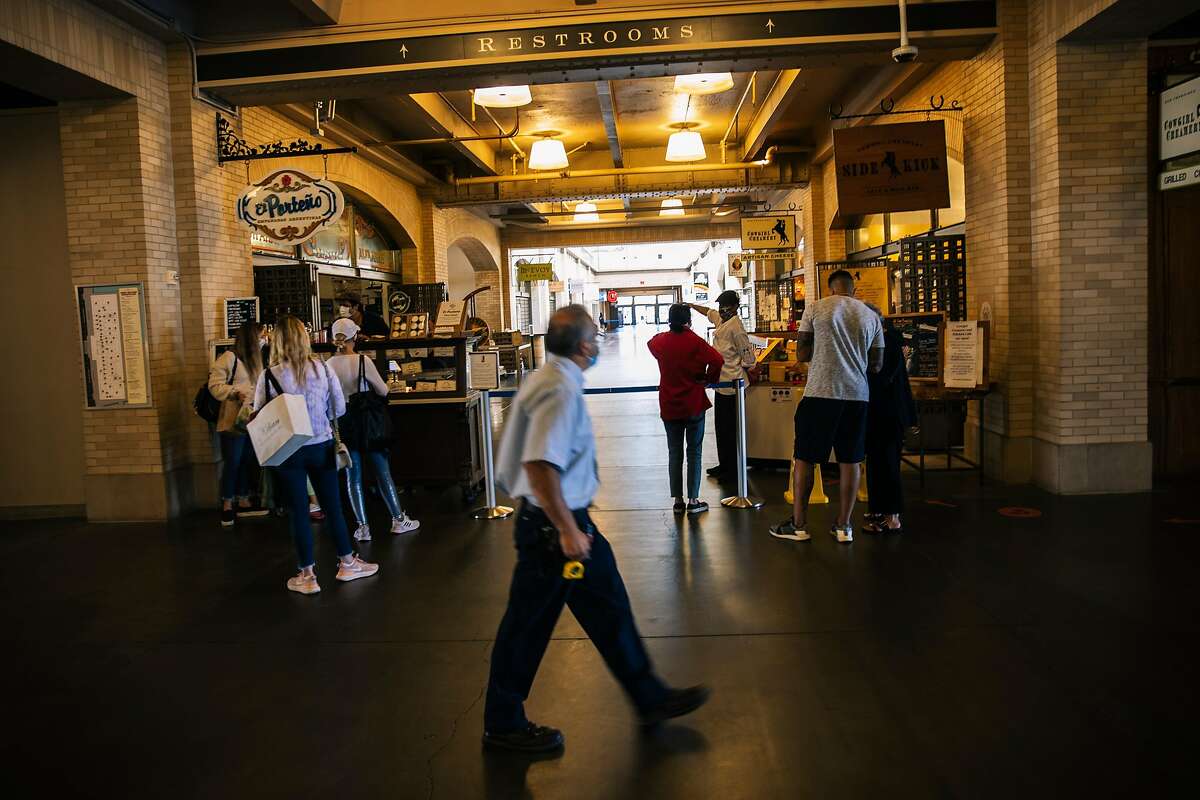 People wait in lines for El Porteno and Cowgirl Creamery along a passage way in the Ferry Building after all interior shops were forced to shut down due to the ongoing COVID-19 pandemic in San Francisco, Calif. on Thursday, July 23, 2020.