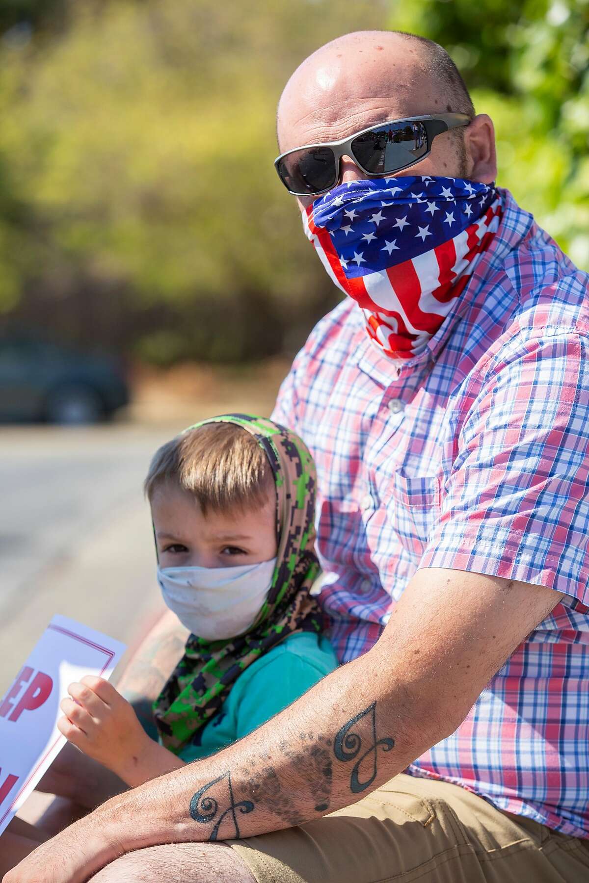 Joe Pelleriti and his son Joe Pelleriti Jr., 3, at a rally outside the Marin County Office of Education on Thursday, July 16, 2020, in San Rafael, Calif. Teachers and their supporters across California are protesting school district plans for in-person learning, amid the coronavirus pandemic. Pelleriti�s spouse Tricia Pelleriti was laid off from her third grade teaching job.