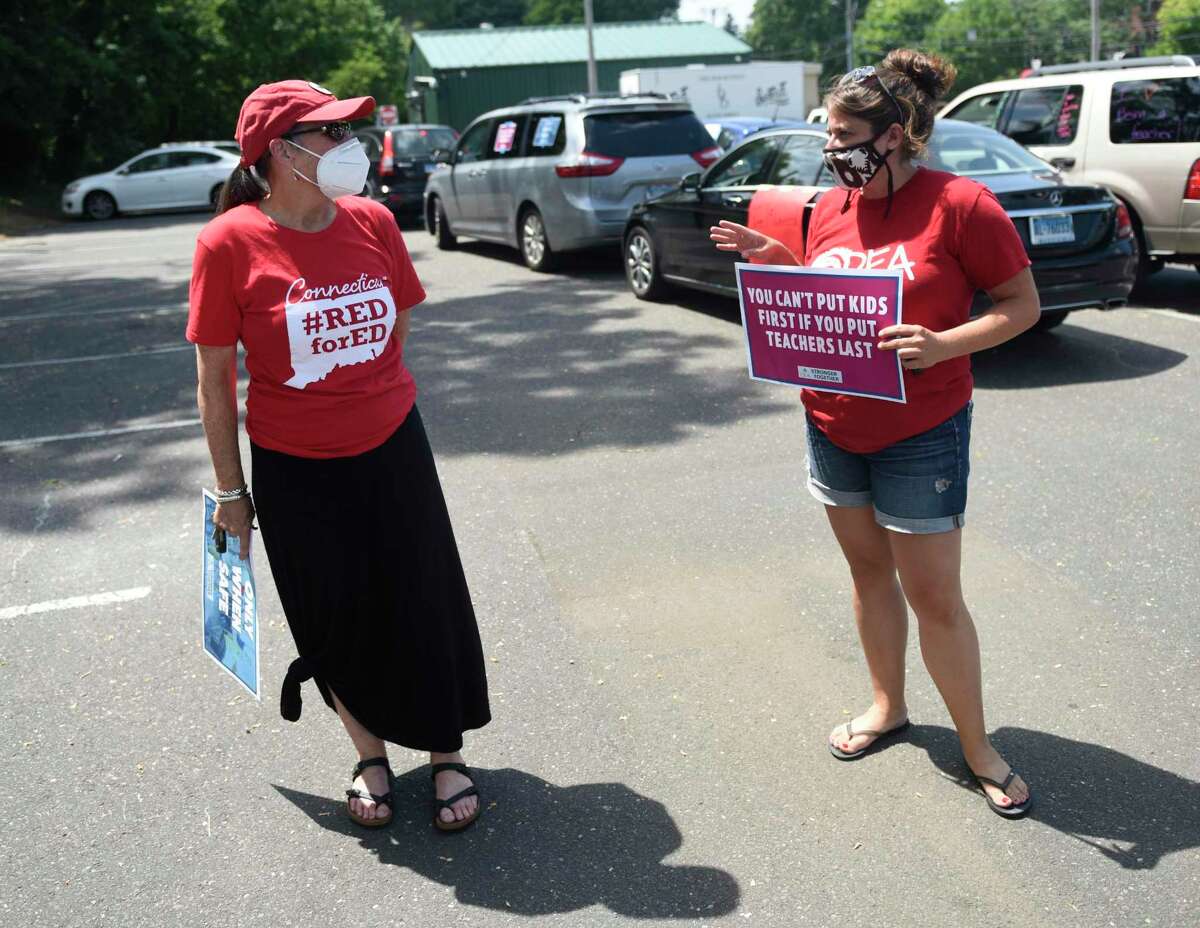 Greenwich Education Association President Carol Sutton, left, and Darien Education Association President Joslyn DeLancey chat before the teachers protest caravan in the Horseneck Lane parking lot in Greenwich, Conn. Thursday, July 30, 2020. The Connecticut Education Association and American Federation of Teachers Connecticut partnered with local union leaders to organize the event demanding the safety of students and teachers as well as state funding for reopening.