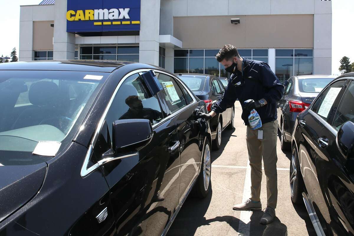 Sales Consultant Jordan Kanady disinfects a Cadillac that a customer will test drive at the San Jose Carmax, on Thursday, July 30, 2020, in San Jose, Calif.