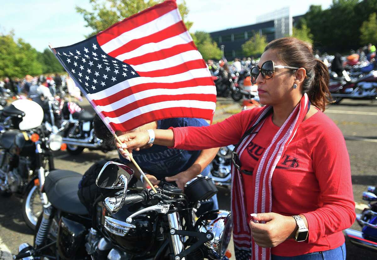 Silvia Flores, of Redding, attaches an American flag to the handlebars as she and husband Jose Flores prepare for the start of the annual CT United Ride, Connecticut's largest 9/11 tribute, in Norwalk, Conn. on Sunday, September 8, 2019.