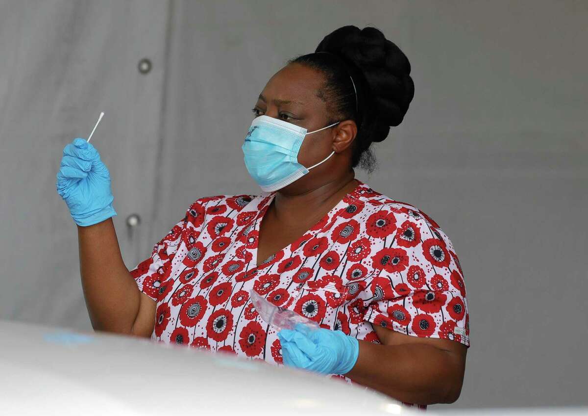 A woman directs a patient on how to self-administer a coronavirus test at Pridgeon Stadium Friday, July 31, 2020, in Cypress.