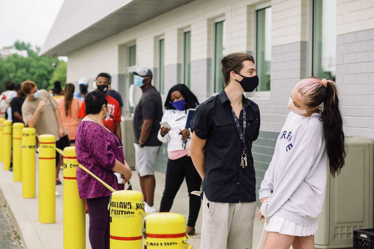 Parker Smith and Chloe Lenox, front, stand at a distance from others outside an Ohio Bureau of Motor Vehicles office on June 30. The state is at risk of a new surge in cases.